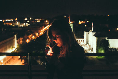 Woman smoking on balcony at night