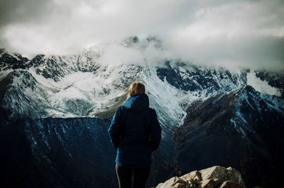 Rear view of woman standing on mountain against sky