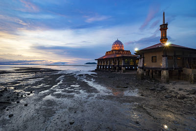 Stilt house against sky during sunset