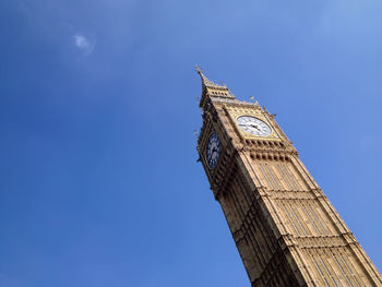 Low angle view of big ben against blue sky on sunny day in city