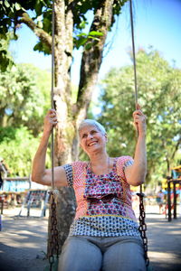 Smiling senior woman sitting on swing at park