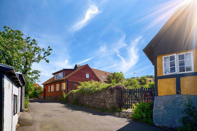 Street by buildings against sky on sunny day