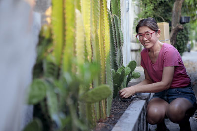 Asian woman planting cactus at home fence