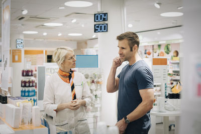 Male customer talking with female owner at pharmacy store