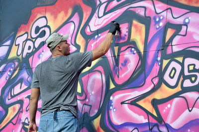 Portrait of young woman standing against graffiti wall