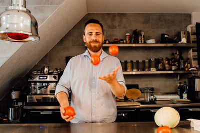 Chef juggling tomatoes while standing at restaurant kitchen
