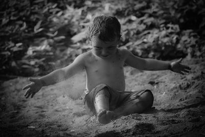 Full length of shirtless boy sitting on land