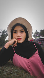 Portrait of beautiful young woman standing against sky