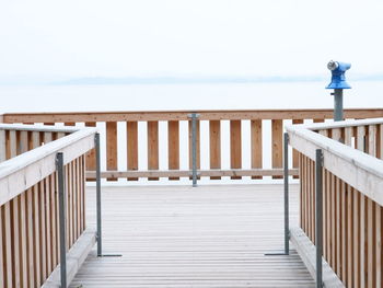 Railing on pier by sea against clear sky