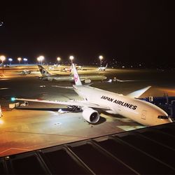 Airplane on airport runway against clear sky at night