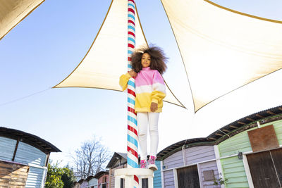 Girl standing on pole near beach huts