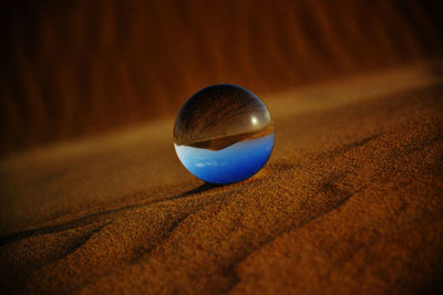 Close-up of crystal ball on sand