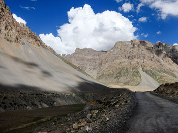 Road amidst rocky mountains against cloudy sky at ladakh