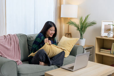 Portrait of young woman sitting on sofa at home
