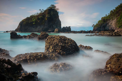 Scenic view of rocks in sea against sky