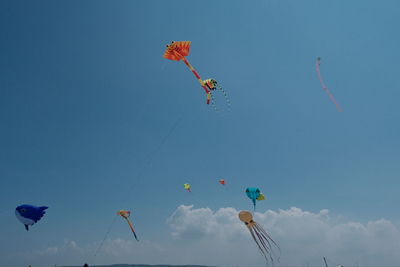 Low angle view of kites flying against clear blue sky