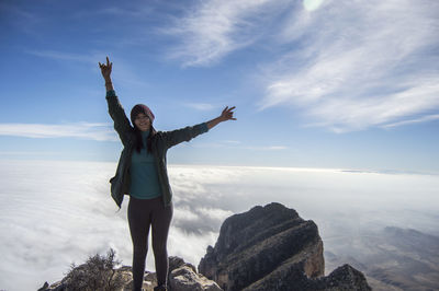 Woman standing on rock against cloudscape