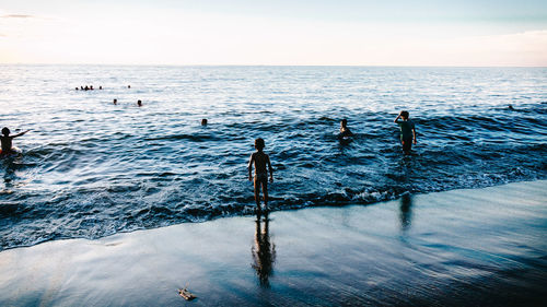 People in sea against sky