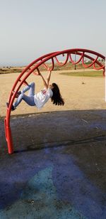 Girl playing at playground against clear sky