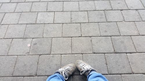 Low section of man standing on cobblestone