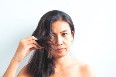 Portrait of young woman holding camera over white background