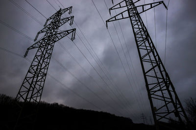 Low angle view of silhouette electricity pylon against sky