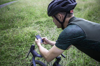 Man riding bicycle while using mobile phone outdoors