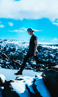 Side view of young man looking at sea against sky