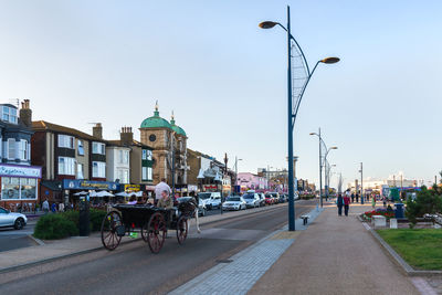 Street by buildings in city against sky