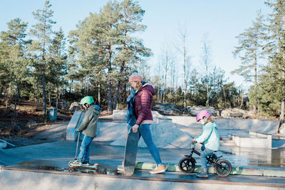 Mom and her kids walking across a skatepark to ride and have fun