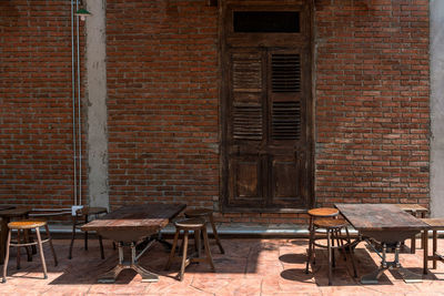 Empty chairs and table against brick wall of old building