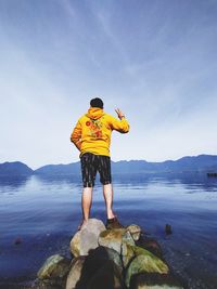 Rear view of man looking at sea against sky