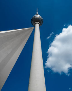 Low angle view of communications tower against cloudy sky