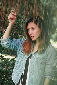 Portrait of beautiful woman standing against plants