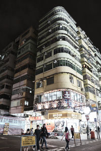 People walking on road against buildings at night