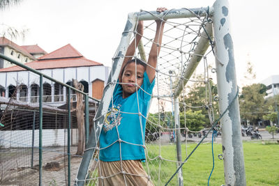 Portrait of boy hanging on fence