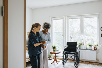Smiling nurse supporting senior woman trying to walk at care home