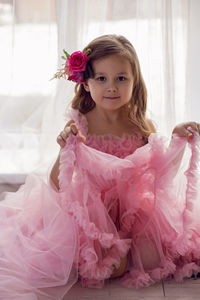 Portrait of a girl in a pink dress and a flower with a rose in her head in the studio