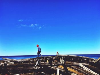 Man standing by sea against clear blue sky