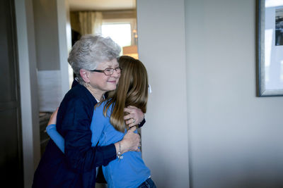 Grandmother embracing granddaughter at home