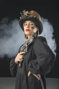 Young woman wearing hat standing against black background