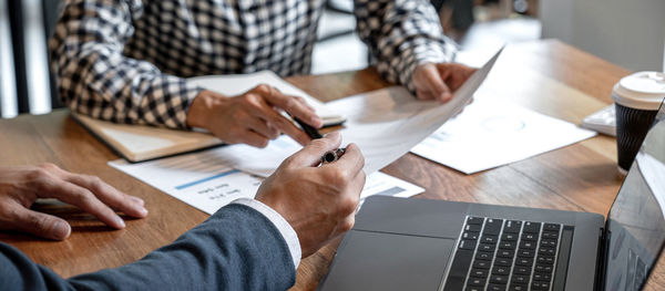 Midsection of businessman using calculator at table