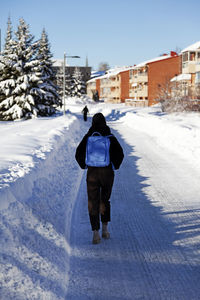 Rear view of woman walking on snow covered field