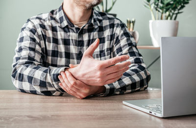 A man suffering from joint pain in his hand and wrist, rheumatoid arthritis and occupational disease