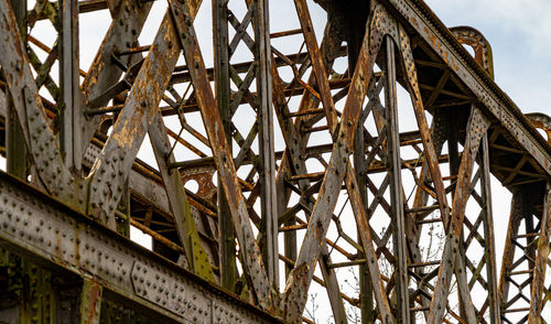 Low angle view of rusty bridge against sky