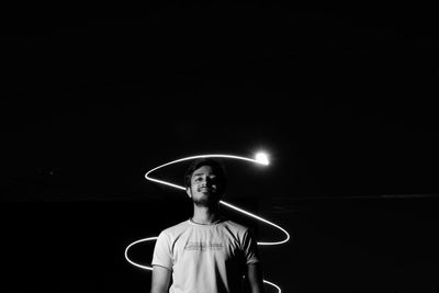 Portrait of young man standing against illuminated light