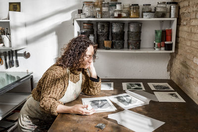 Female artist inspecting some pieces of hand made printings.