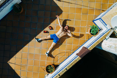 High angle view of young man sitting on wall