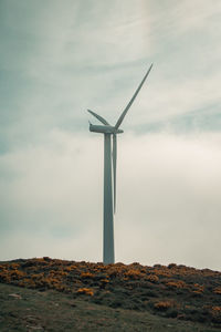 Windmill on landscape against sky