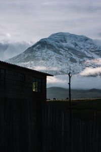 Scenic view of snowcapped mountains against blue sky with a house